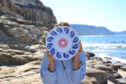 Person holding a decorative plate with a beach and rocky landscape in the background