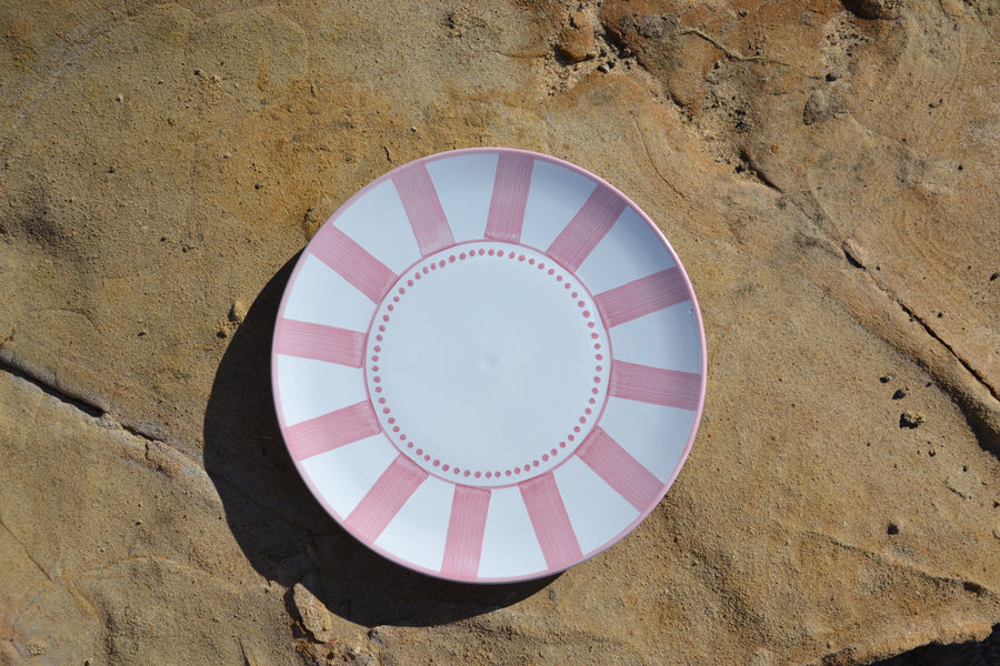 White plate with pink stripes on a textured brown surface