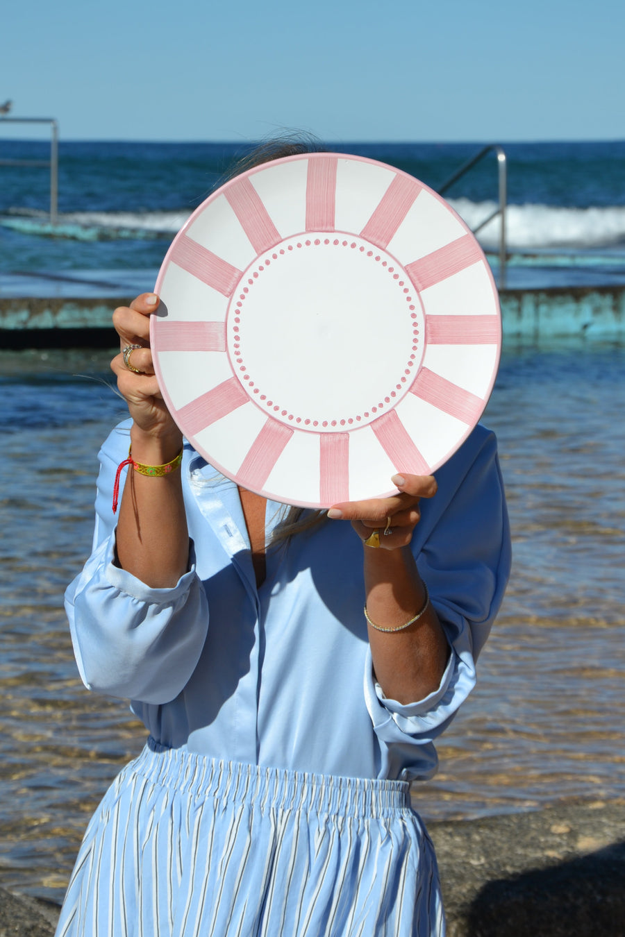 Person holding a pink and white striped object by a body of water
