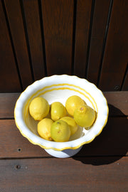 White bowl with yellow lemons on a wooden surface