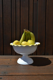 White ceramic fruit bowl with fruit on a wooden surface
